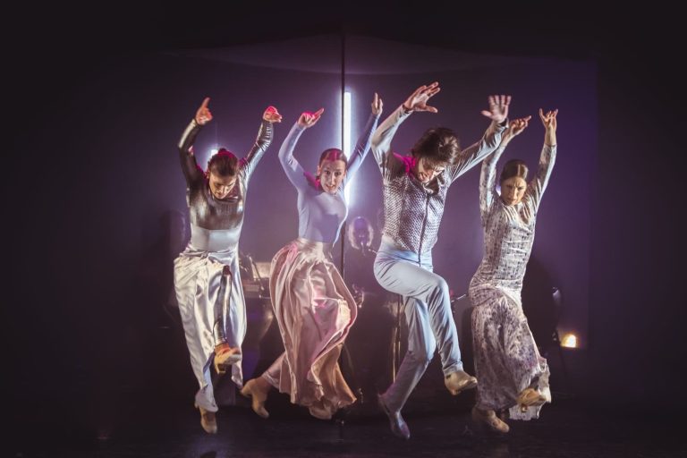 Bailaores saltando en el escenario con ropa brillantes