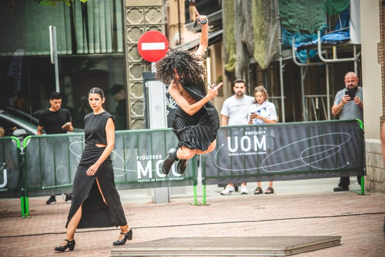 Hombre vestido de negro saltando en una presentación de danza en la calle