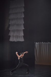Hombre bailando flamenco moderno en un escenario con unos detalles de tejido